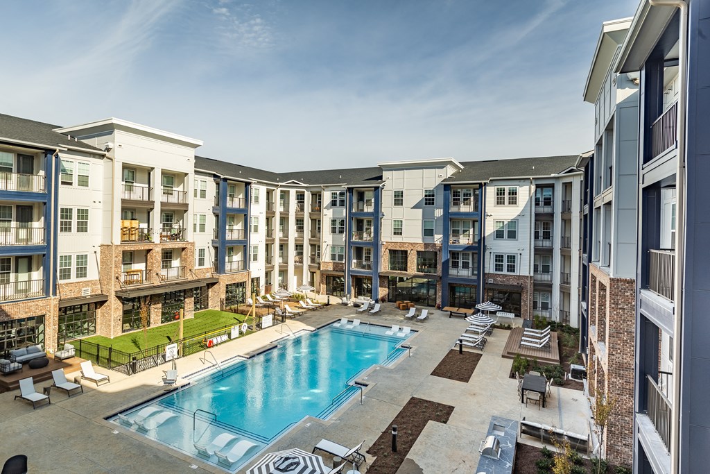 an apartment building with a swimming pool and lounge chairs at The Louis Apartment Flats, Louisville