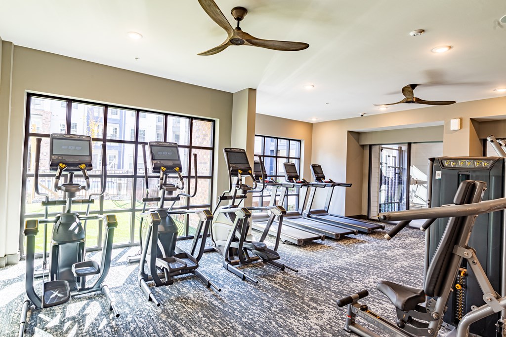 a gym with treadmills and other exercise equipment in a room with windows at The Louis Apartment Flats, Louisville, 40241