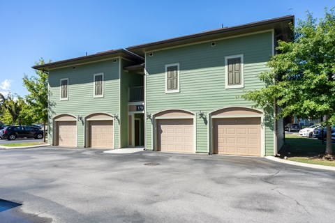 A two-story building with a green exterior and three garage doors.