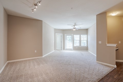 A spacious room with a carpeted floor and a ceiling fan.