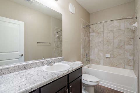 A bathroom with a marble countertop and a white sink.