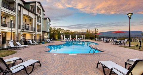 a swimming pool with chairs and umbrellas next to a building at Integra Vista Apartments, Hixson, TN