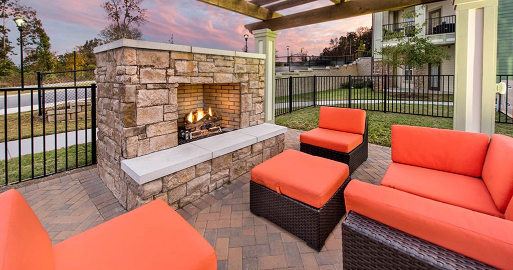 outdoor seating around a stone fireplace on a patio with orange furniture