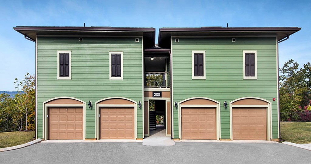a green building with brown garage doors