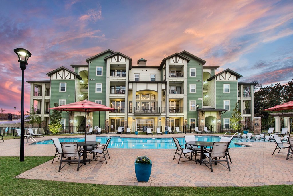 a swimming pool with patio furniture and a building in the background