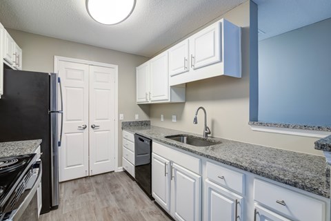 A kitchen with white cabinets and a black refrigerator.