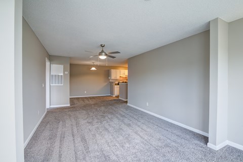 A spacious room with a ceiling fan and carpeted floor.