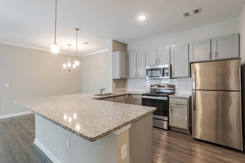 A kitchen with a granite countertop and stainless steel appliances.