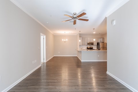 A spacious room with a ceiling fan and hardwood floors.