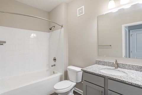 A white toilet sits next to a white bathtub in a bathroom.