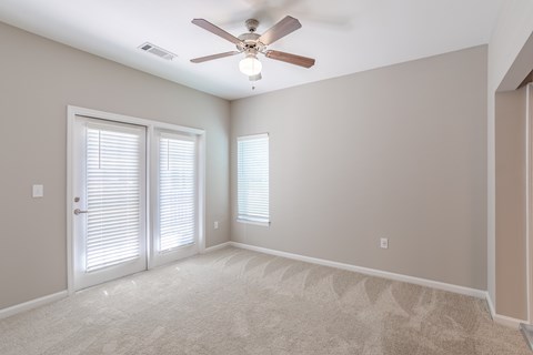 A room with a ceiling fan and two windows with blinds.