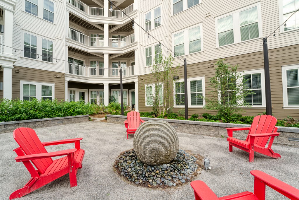 a fire pit with red chairs in front of an apartment building at Lyric at Norton Commons Apartments, Prospect, Kentucky