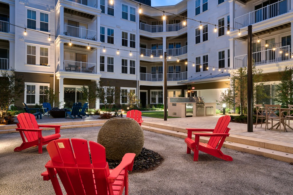 a courtyard with red chairs in front of an apartment building at Lyric at Norton Commons Apartments, Prospect, 40059