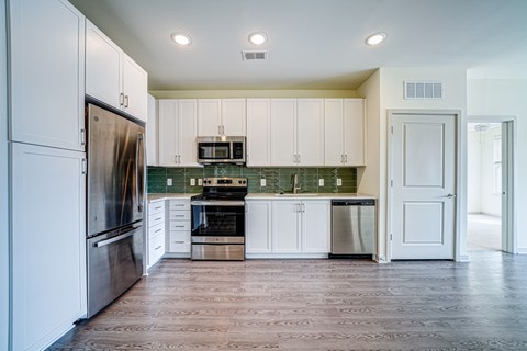 A kitchen with white cabinets and a wooden floor.