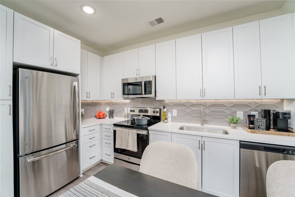 a kitchen with white cabinets and stainless steel appliances at Lyric at Norton Commons Apartments, Prospect, KY