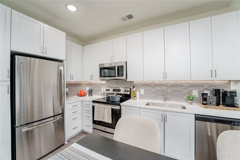 a kitchen with white cabinets and stainless steel appliances
