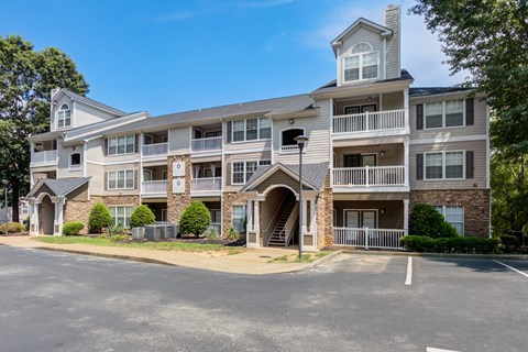 A large apartment building with a parking lot in front.