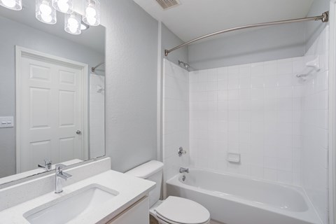 A white bathroom with a toilet, sink, and bathtub.