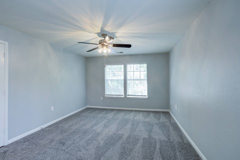 A room with a ceiling fan and carpeted floor.