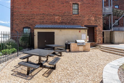A brick building with a black fence and a picnic table in front.