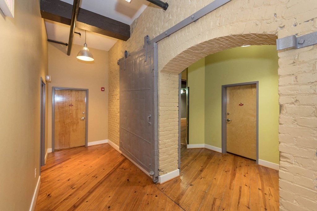 a living room with a wood floor and a door at Mayton Transfer Lofts, Petersburg, 23803