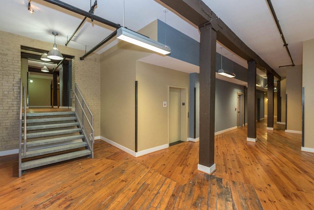the interior of an empty building with a staircase and wood floors at Mayton Transfer Lofts, Virginia, 23803