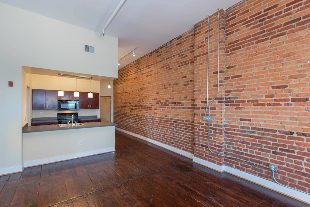 a living room with a brick wall and a kitchen at Mayton Transfer Lofts, Virginia