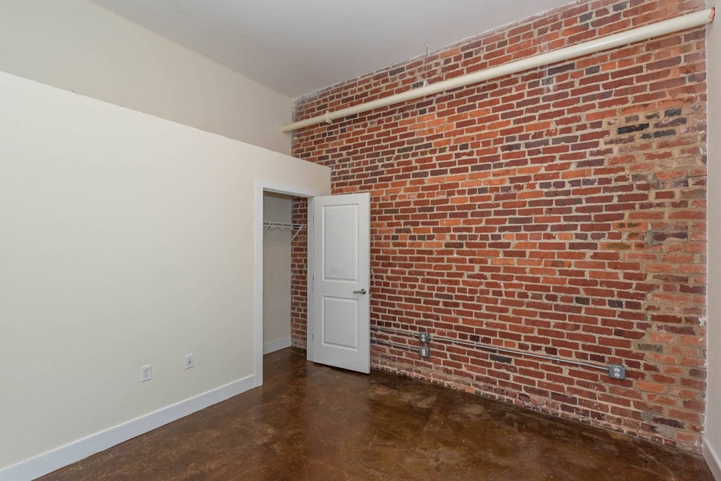 a room with a brick wall and a white door at Mayton Transfer Lofts, Petersburg, VA