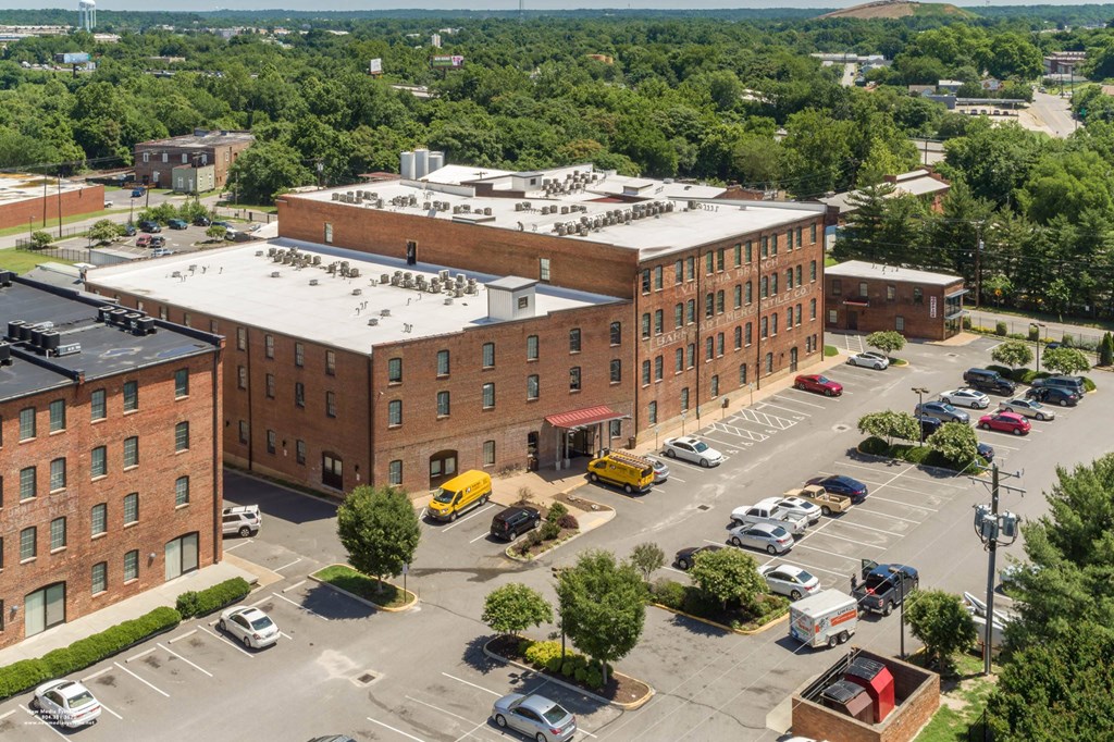 an aerial view of a large brick building with a white roof and a parking lot at Mayton Transfer Lofts, Petersburg, VA