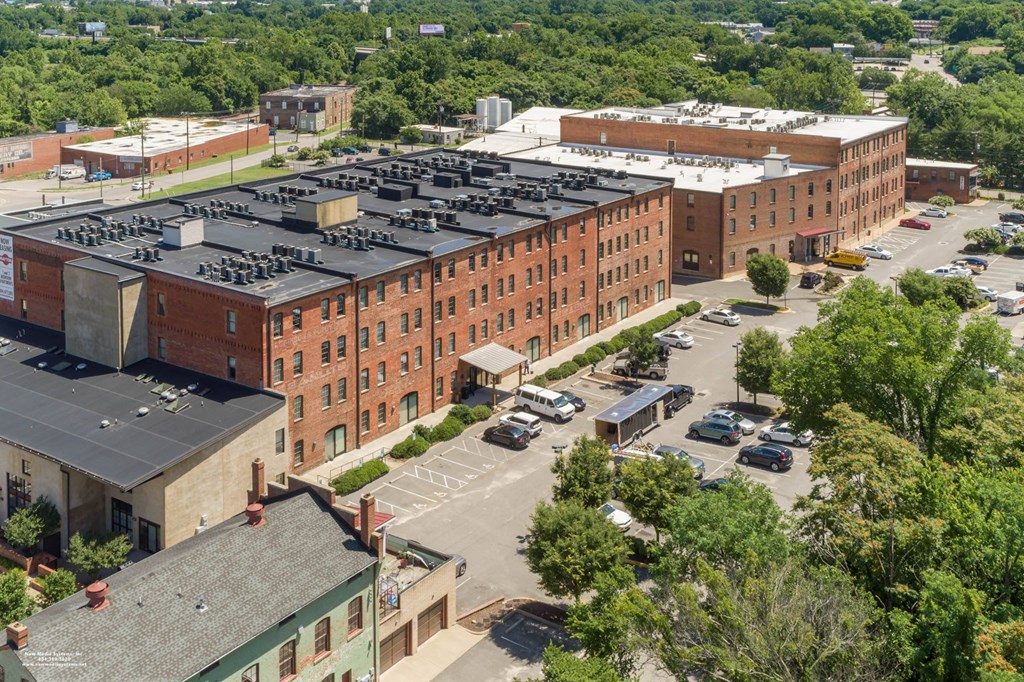an aerial view of a large brick building with a parking lot at Mayton Transfer Lofts, Virginia, 23803