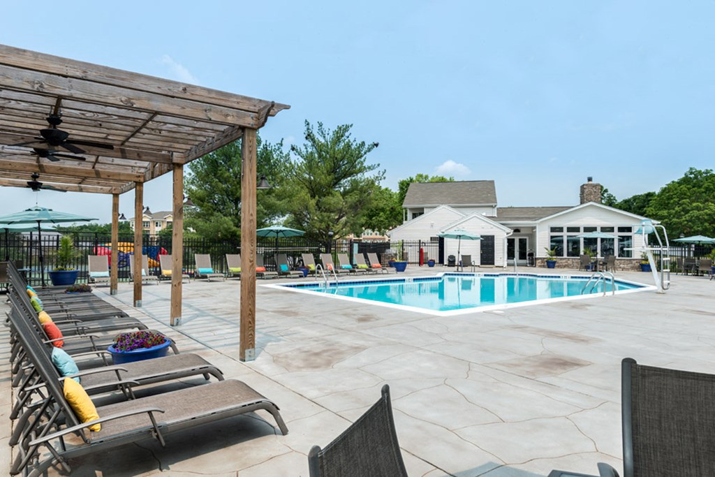 a swimming pool with lounge chairs and umbrellas at Misty Ridge Apartments, Woodbridge Virginia