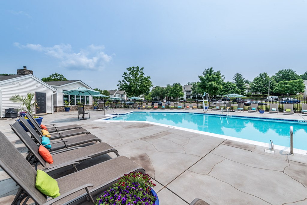 a swimming pool with lounge chairs and umbrellas at Misty Ridge Apartments, Virginia