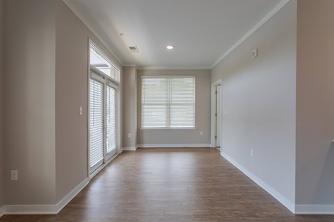 A room with wooden floors and a window with blinds.