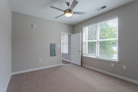 A room with a ceiling fan and a window with blinds.