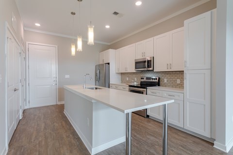 A kitchen with white cabinets and a white island.