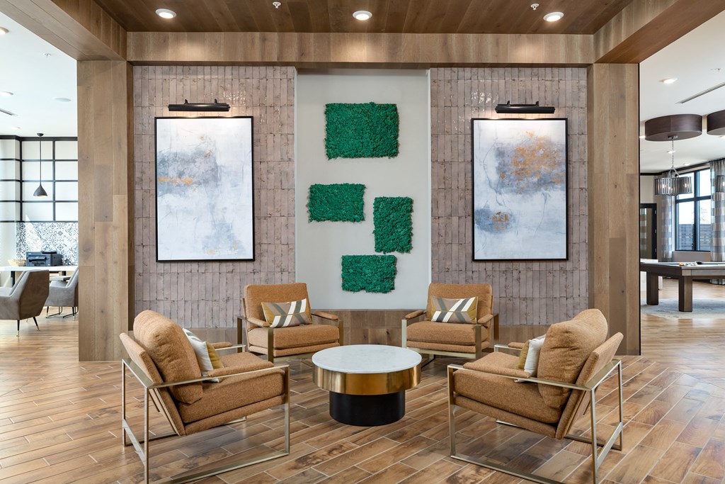 a lobby with a table and chairs and two paintings on the wall at The Flats at Southlawn Apartments, Lawrenceville