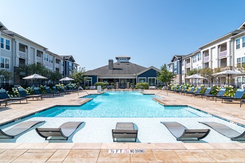 A pool surrounded by lounge chairs and umbrellas with a sign that says "NO DIVING".