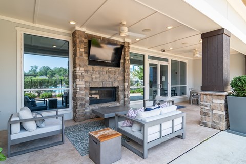 A modern living room with a stone fireplace and a flat screen TV mounted above it.