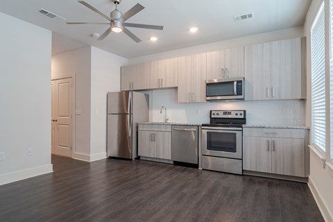 A modern kitchen with stainless steel appliances and wooden floors.