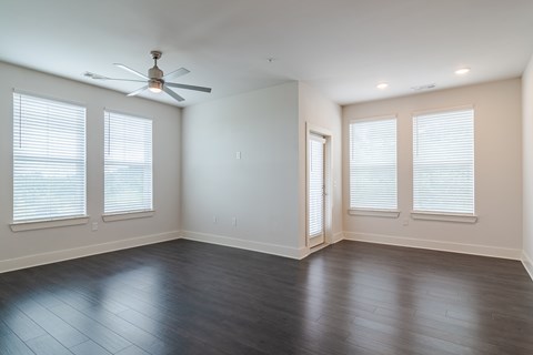 A room with a ceiling fan and wood flooring.