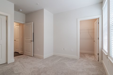 A white room with a carpeted floor and two open doors.