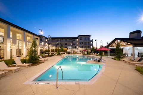 a swimming pool at night with a building in the background at The Quincy Apartments, Acworth, 30102