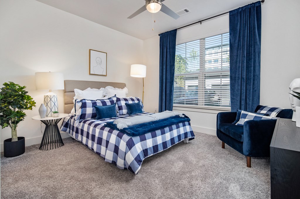 a bedroom with a bed and a chair and a ceiling fan a bedroom with a bed and a chair and a ceiling fan at The Quincy Apartments, Acworth, Georgia