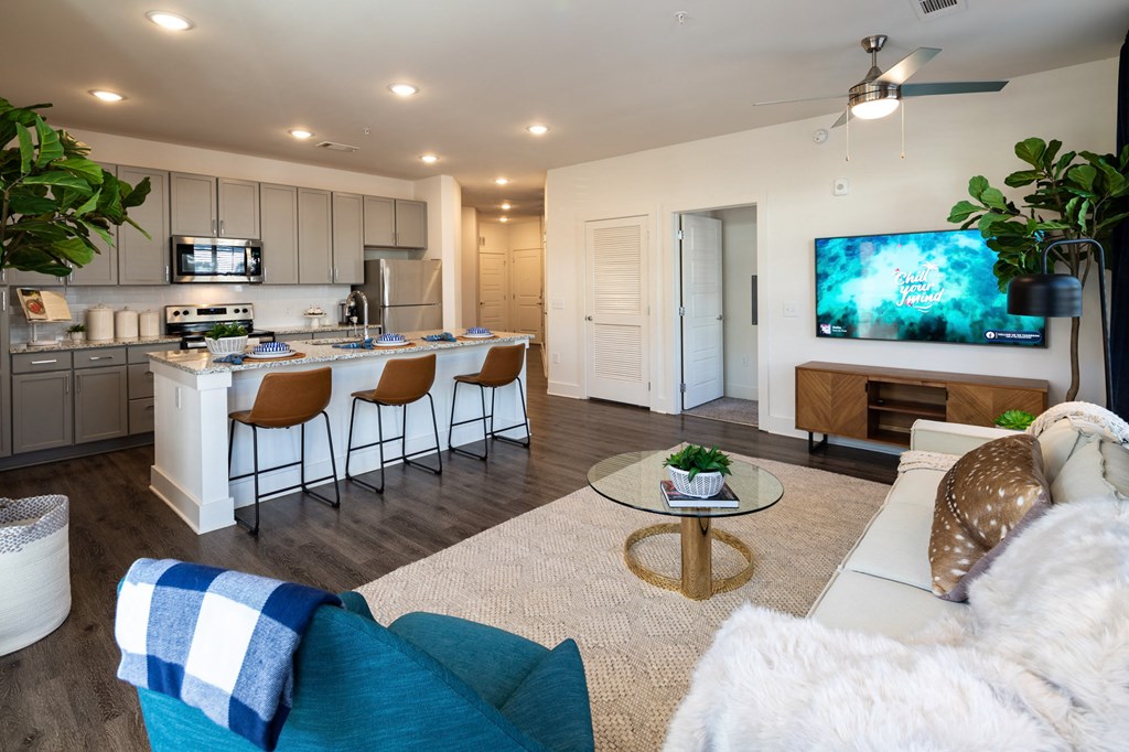 an open living room and kitchen with a large screen tv at The Quincy Apartments, Acworth, GA, 30102
