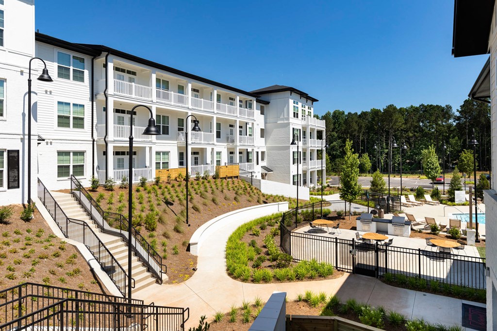 a view of the exterior of an apartment building with a courtyard and benches at The Quincy Apartments, Acworth, GA