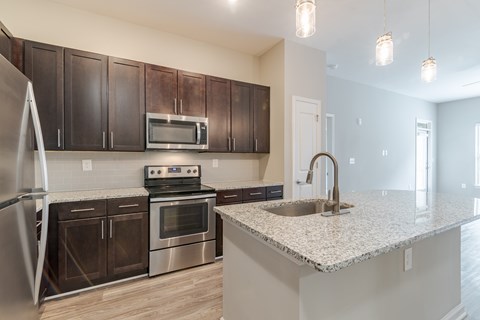 A kitchen with a stove, oven, refrigerator, and microwave.
