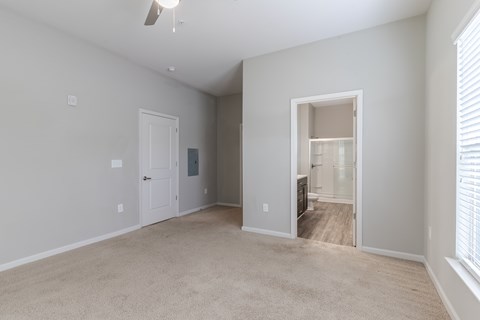 A spacious room with a carpeted floor and a ceiling fan.