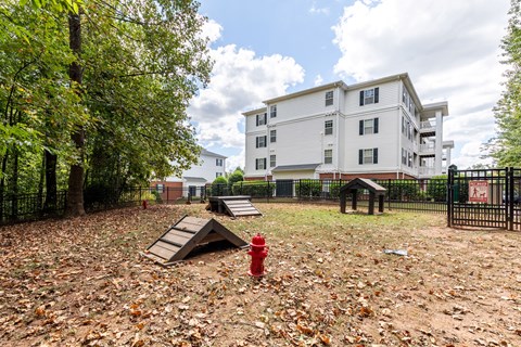 A red fire hydrant sits in a field of leaves in front of a white apartment building.