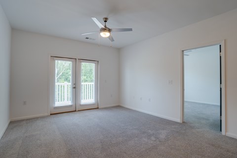 A room with a ceiling fan and carpeted floor.