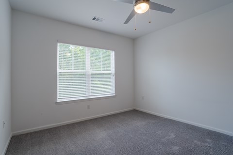 A room with a ceiling fan and a window with blinds.
